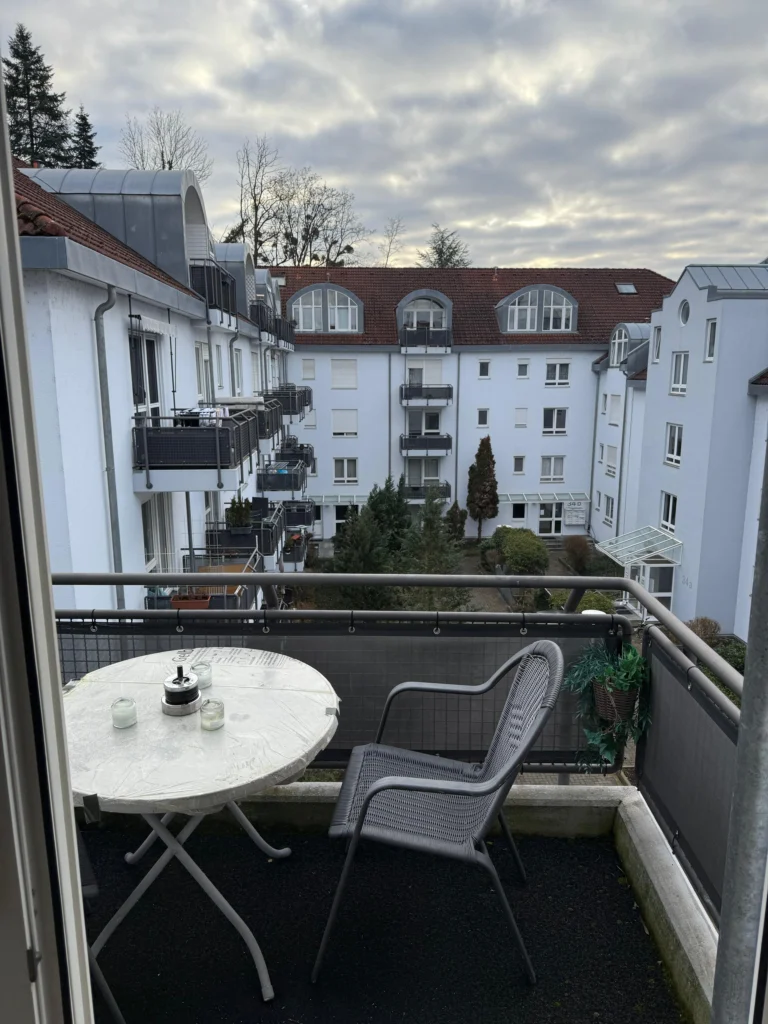 Balkon einer Unterkunft für Arbeiter in Lörrach Mitte in der Bergstraße 36A mit zwei Stühlen und einem Tisch.