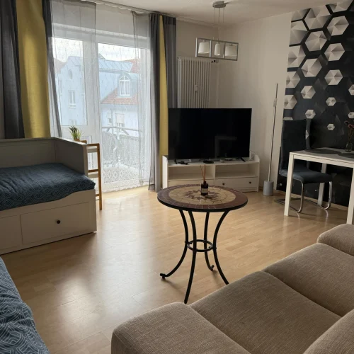 Der Schlaf-Wohnbereich für die Arbeiter und Fachkräfte in der Monteurswohnung Lörrach-Mitte mit zwei Einzelbetten und eine Couch mit Fernseher.