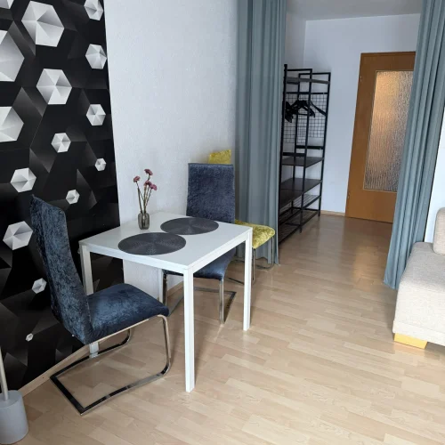 Ein Tisch mit zwei Stühlen in der Monteurswohnung Lörrach-Mitte in der Bergstraße 36A. Im Hintergrund befindet sich der Eingangsbereich.